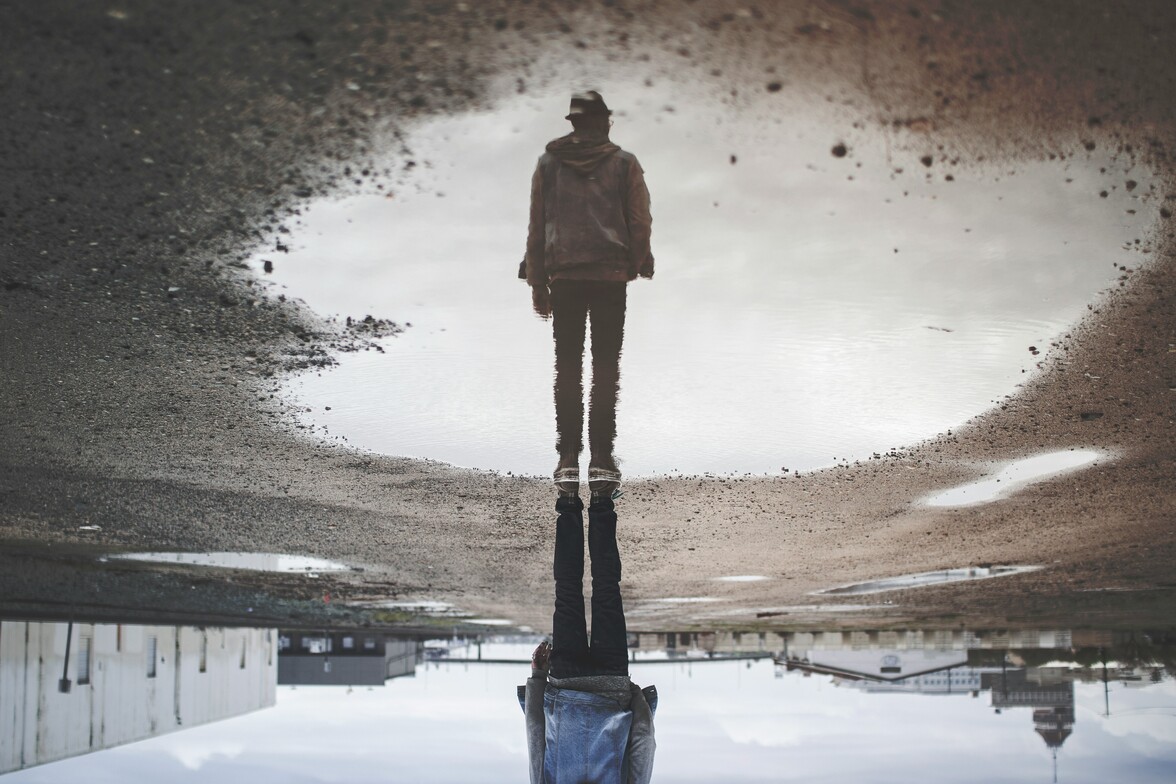reflected image of a person standing in a puddle